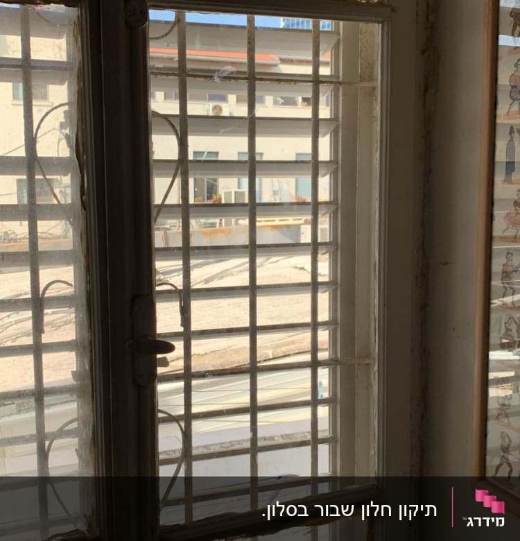 חלון זכוכית עם סורגים ומסגרת מתקלפת